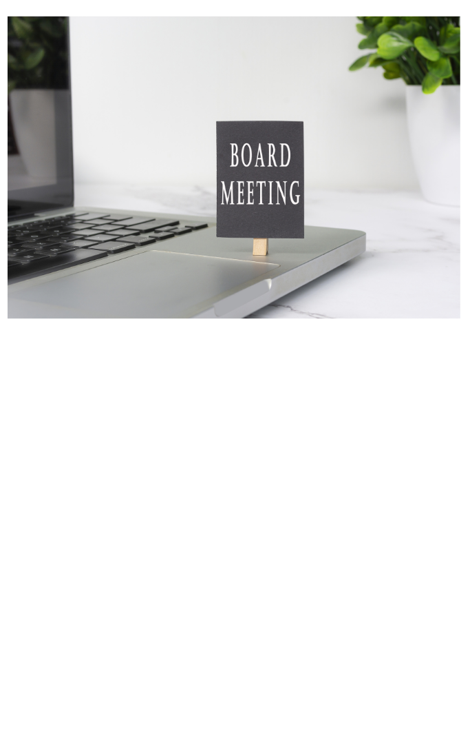 Laptop computer on a desk open with a small "Board Meeting" standing near the keyboard